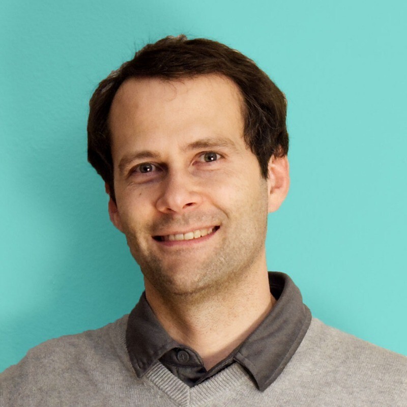 LightScalpel CEO Daniel Chase smiling in a sweater on a portrait photo